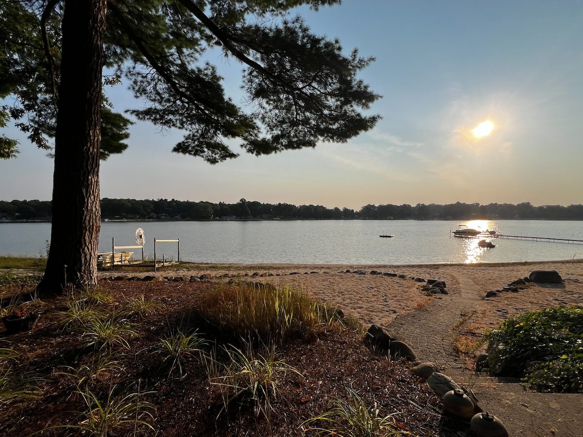 A warm golden sunset over the calm water at the MCM Lake House in Twin Lake, an Open Water co-hosted home